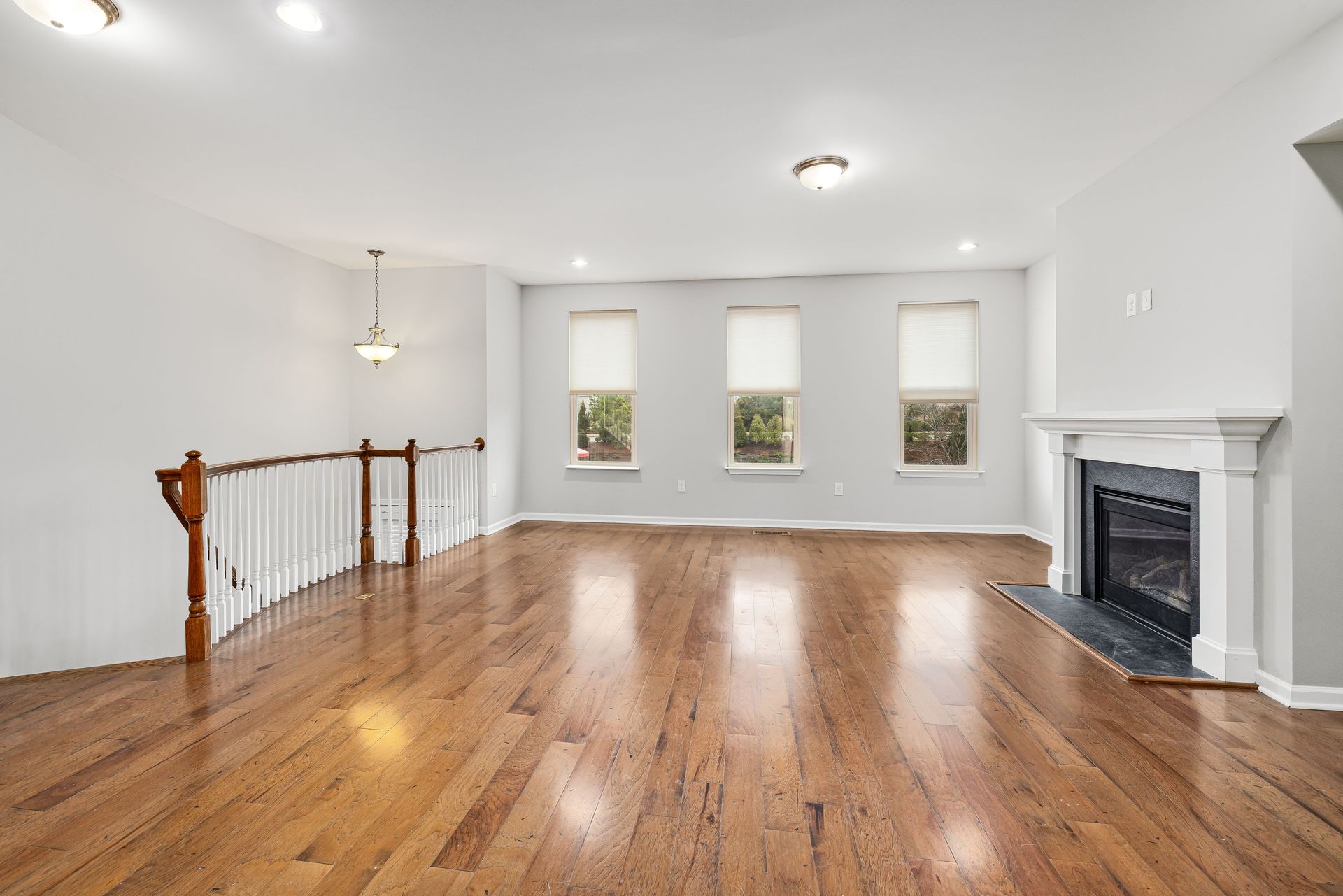 Bright and spacious modern living room with wooden floors and a fireplace, perfect for interior design inspiration.